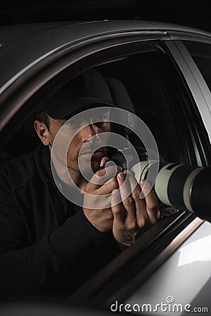 male paparazzi in cap doing surveillance by camera with object glass from his Stock Photo