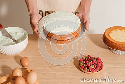 Male pastry chef is holding sponge cake with many various ingredients. Making sponge cake process Stock Photo