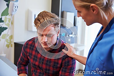 Male Patient Being Reassured By Nurse In Hospital Room Stock Photo