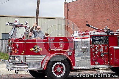 Male person waving from a red fire engine car in Wilmington Editorial Stock Photo