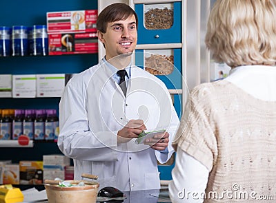 Male pharmacist talking to customer at pharmacy Stock Photo