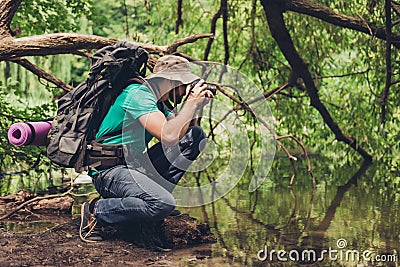 Male photographer is near the lake outdoors in the spring wood, taking shot of beautiful nature! He is a tourist, hiking in jungle Stock Photo