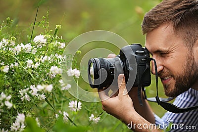 Male photographer taking picture of plants with professional camera outdoors Stock Photo