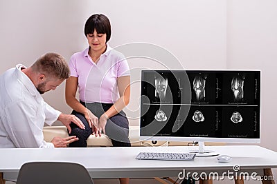 Male Physiotherapist Examining The Knee Pain Of Female Patient Stock Photo