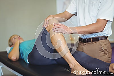 Male physiotherapist giving knee massage to female patient Stock Photo