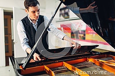 Male pianist opens the lid of black grand piano Stock Photo