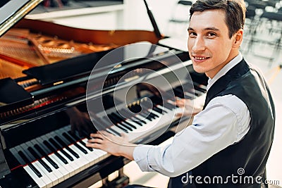 Male pianist poses at the black grand piano Stock Photo