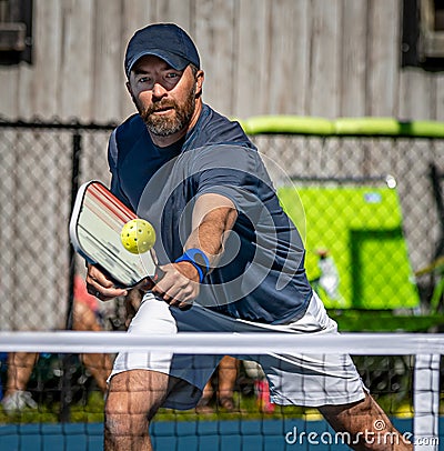 Male pickelball player reaches for the ball during a tournament Stock Photo