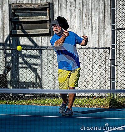 Male pickleball player hits the ball from the baseline Stock Photo