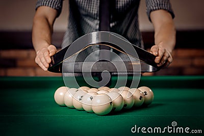 Male player puts white balls with triangle in Russian billiards on green table Stock Photo