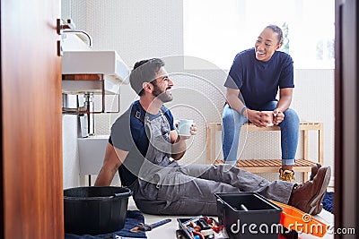 Male Plumber With Female Apprentice Taking A Break From Fixing Leaking Sink In Home Bathroom Stock Photo