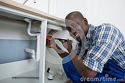 Male Plumber Fixing Pipe Of Sink Stock Photo