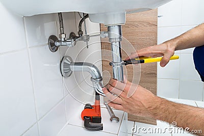 Male plumber fixing sink in bathroom Stock Photo