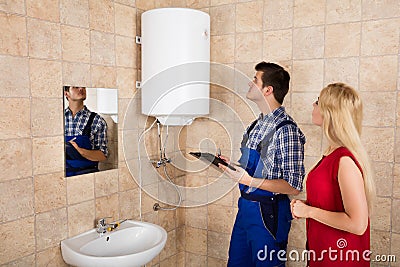 Male Plumber Holding Clipboard Checking Electric Boiler Stock Photo