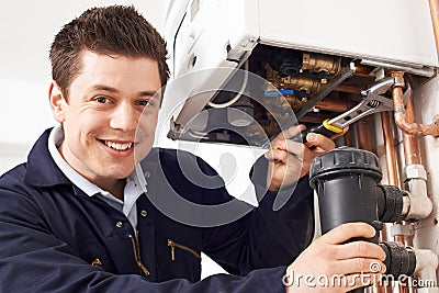 Male Plumber Working On Central Heating Boiler Stock Photo