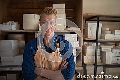 Male potter standing with arms crossed in pottery workshop Stock Photo