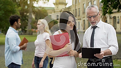 Male professor discussing thesis with asian female student near university Stock Photo