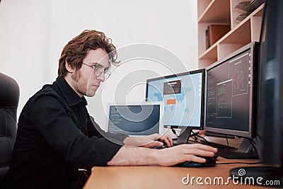 Male programmer working on desktop computer with many monitors at office in software develop company. Website design Stock Photo