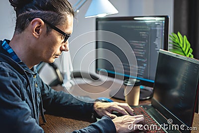 Male programmer is writing program code on a laptop at home. The concept of software development Stock Photo