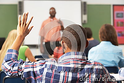 Male Pupil Raising Hand In Class Stock Photo