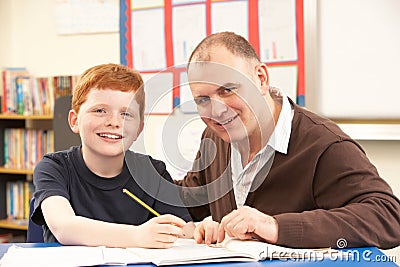 Male Pupil Studying in classroom with teacher Stock Photo