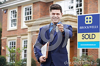 Male Realtor Standing Outside Residential Property Holding Keys Stock Photo