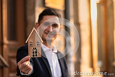 Male realtor standing outside residential property holding wood house Stock Photo