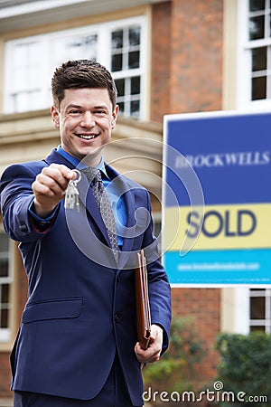 Male Realtor Standing Outside Residential Property Holding Keys Stock Photo