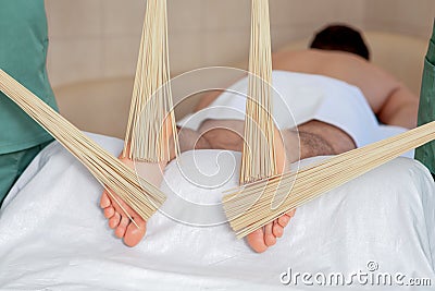 Male receiving feet massage with bamboo brooms Stock Photo