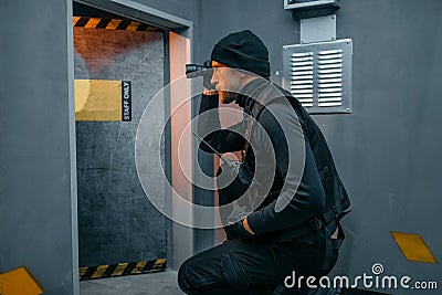 Male robber in black uniform holds gun and lantern Stock Photo