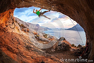 Male rock climber climbing along a roof in a cave Stock Photo