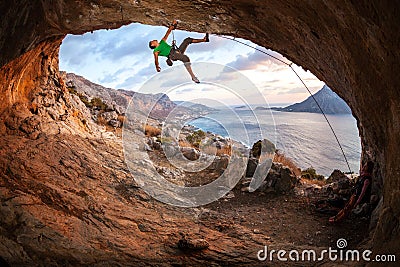 Male rock climber climbing along a roof in a cave Stock Photo