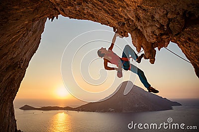 Male rock climber hanging with one hand on challenging route on cliff Stock Photo