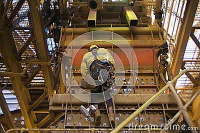 Male rope access industry worker wearing safety harness, fall protection helmet hanging working on Y hang rope position Stock Photo