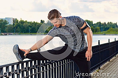 Male runner doing stretching exercise, preparing for workout in Stock Photo