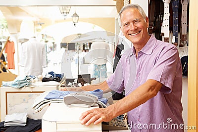 Male Sales Assistant At Checkout Of Clothing Store Stock Photo