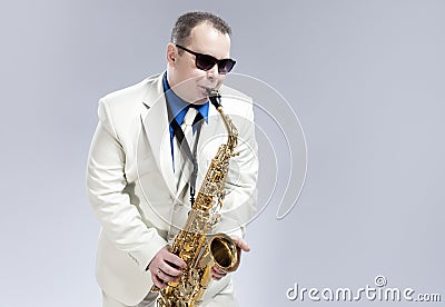 Male Saxophone Player Performing On Alto Saxo In White Suit and Sunglasses Against White Stock Photo