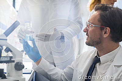 Male Scientist Working With Microscope, Team In Laboratory Doing Research, Man And Woman Making Scientific Experiments Stock Photo