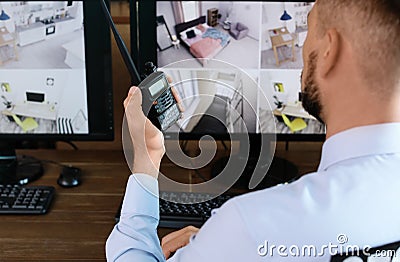Male security guard with portable transmitter monitoring modern CCTV cameras indoors Stock Photo
