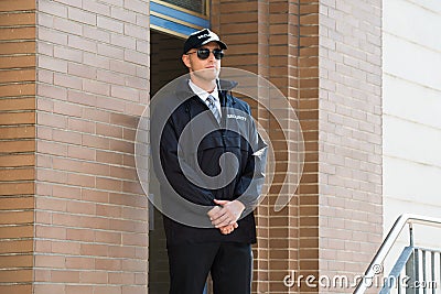 Male Security Guard Standing At The Entrance Stock Photo