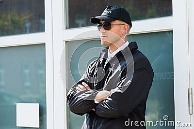 Male Security Guard Standing At The Entrance Stock Photo