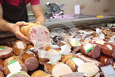 Male seller holding piece of deli meat in butcher shop Stock Photo