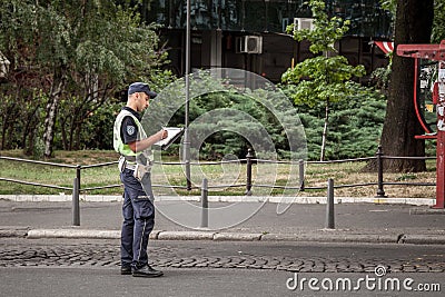 Male Serbian police officer in uniform writing a ticket in Belgrade. He belongs to the civilian police force of the country Editorial Stock Photo