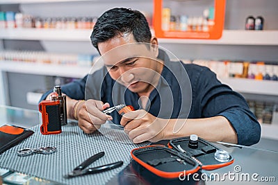 male shopkeeper changing the vape cotton coil seriousely Stock Photo