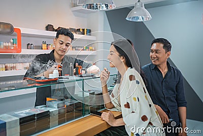 male shopkeeper changing the vape cotton in front of the vaping woman Stock Photo