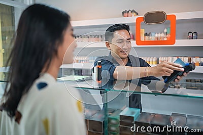 male shopkeeper helping the female customer to paying the vape stuff Stock Photo