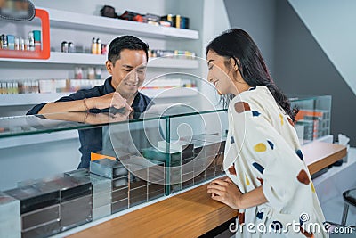 male shopkeeper pointing on the vape mods inside the display table Stock Photo