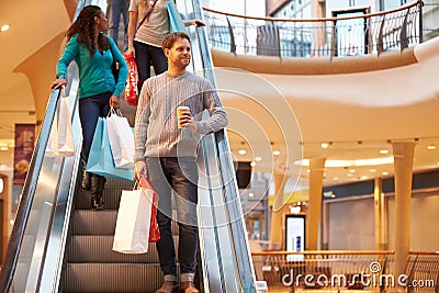 Male Shopper On Escalator In Shopping Mall Stock Photo