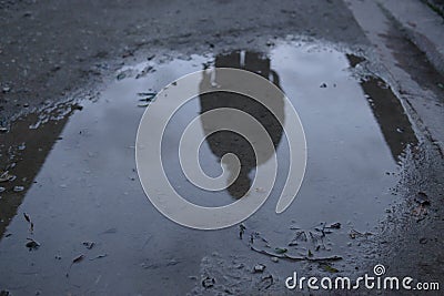 Male silhouette reflected in dark puddle cloud ominous spooky Stock Photo