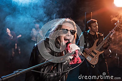 Male singer with microphone and rock and roll band performing hard rock music Stock Photo